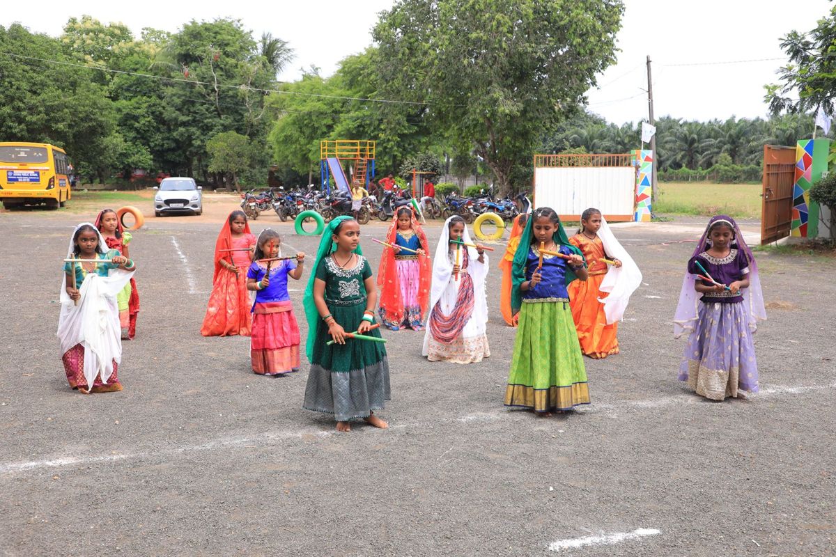 Girls in colourful dresses dancing on the school ground